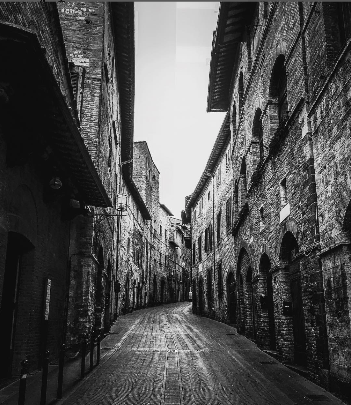 Black-and-white photograph of a winding street between brick buildings in Strasbourg.